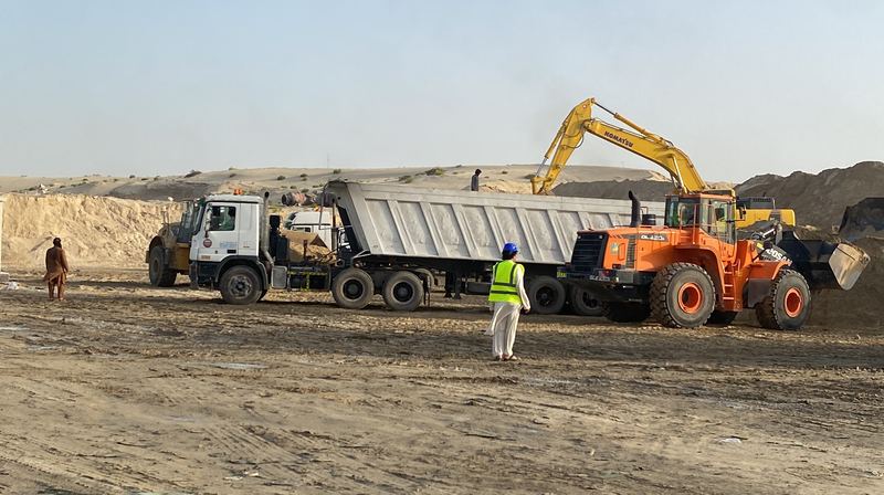 Excavator and wheel loader loading a tipper trailer at an earthworks site